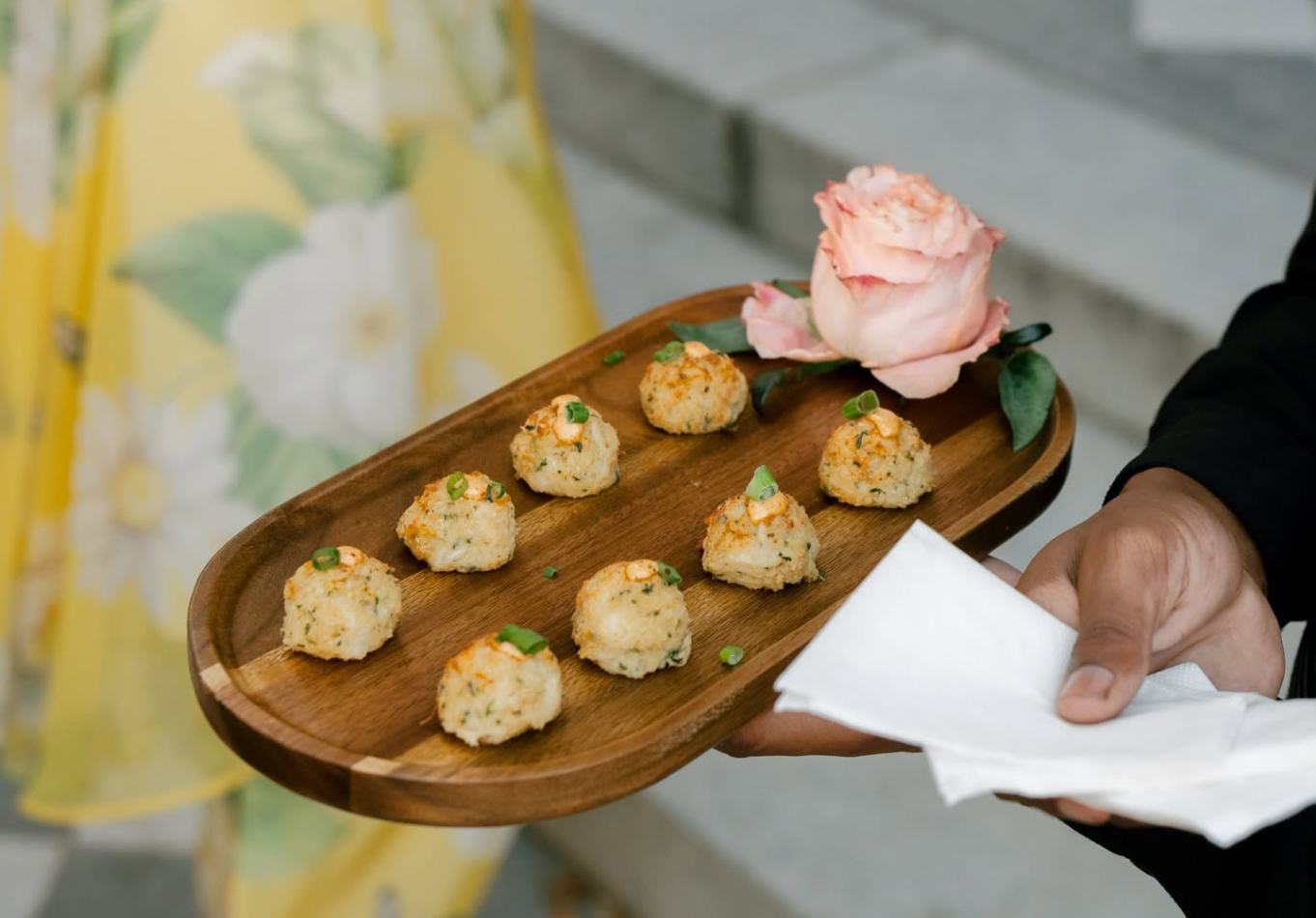 Hamby Catering server passing mini crab cakes on a wooden tray