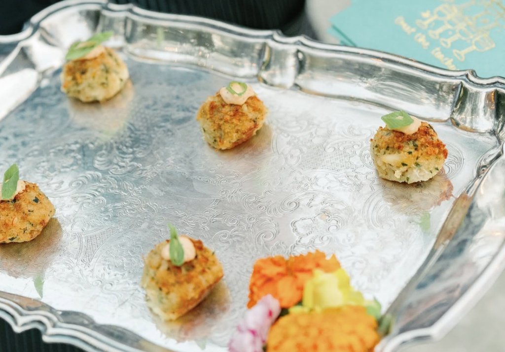 Mini crab cakes with sauce and green onion served on a silver tray
