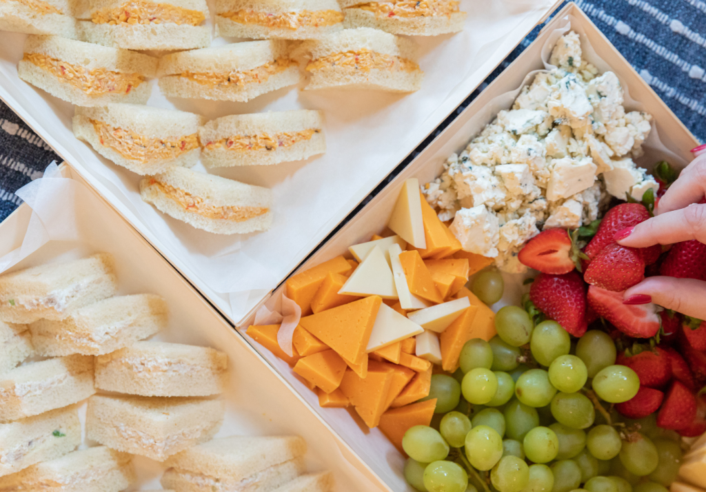 Assorted tea sandwiches, cheeses, grapes, strawberries and chicken salad arranged for wedding day getting-ready refreshments.